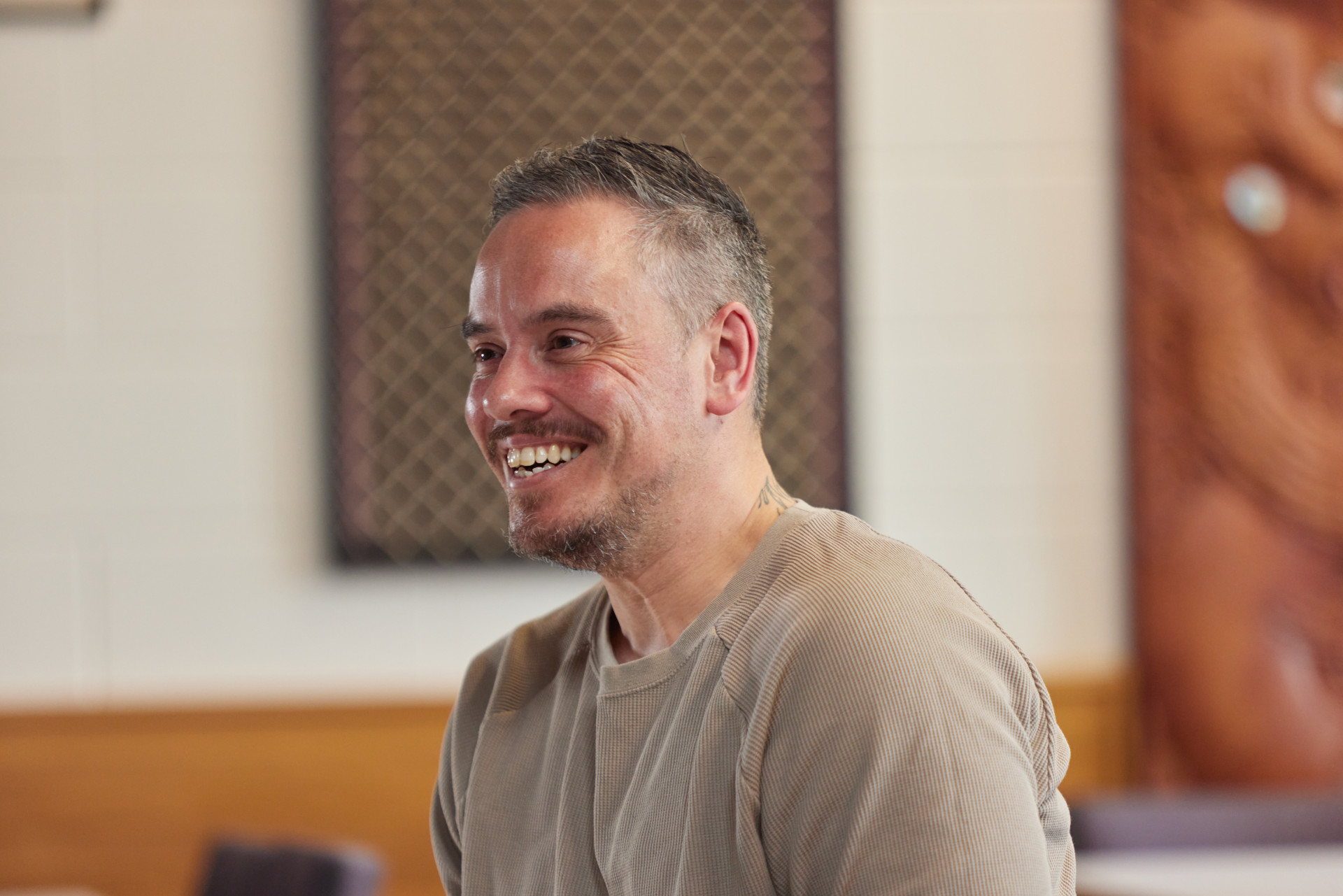 a man smiles as he sits in a room