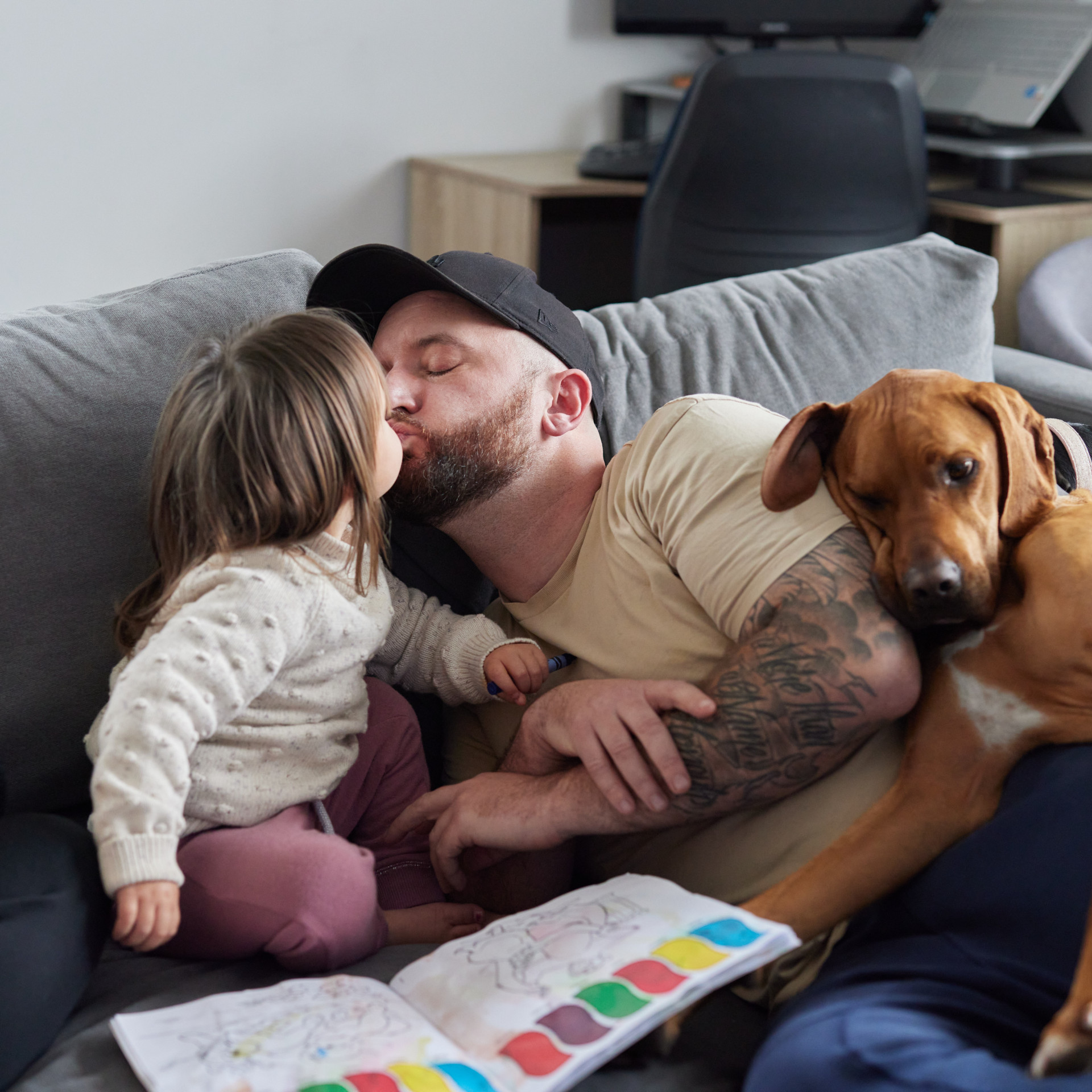 a man laying on a couch with a little girl and a dog