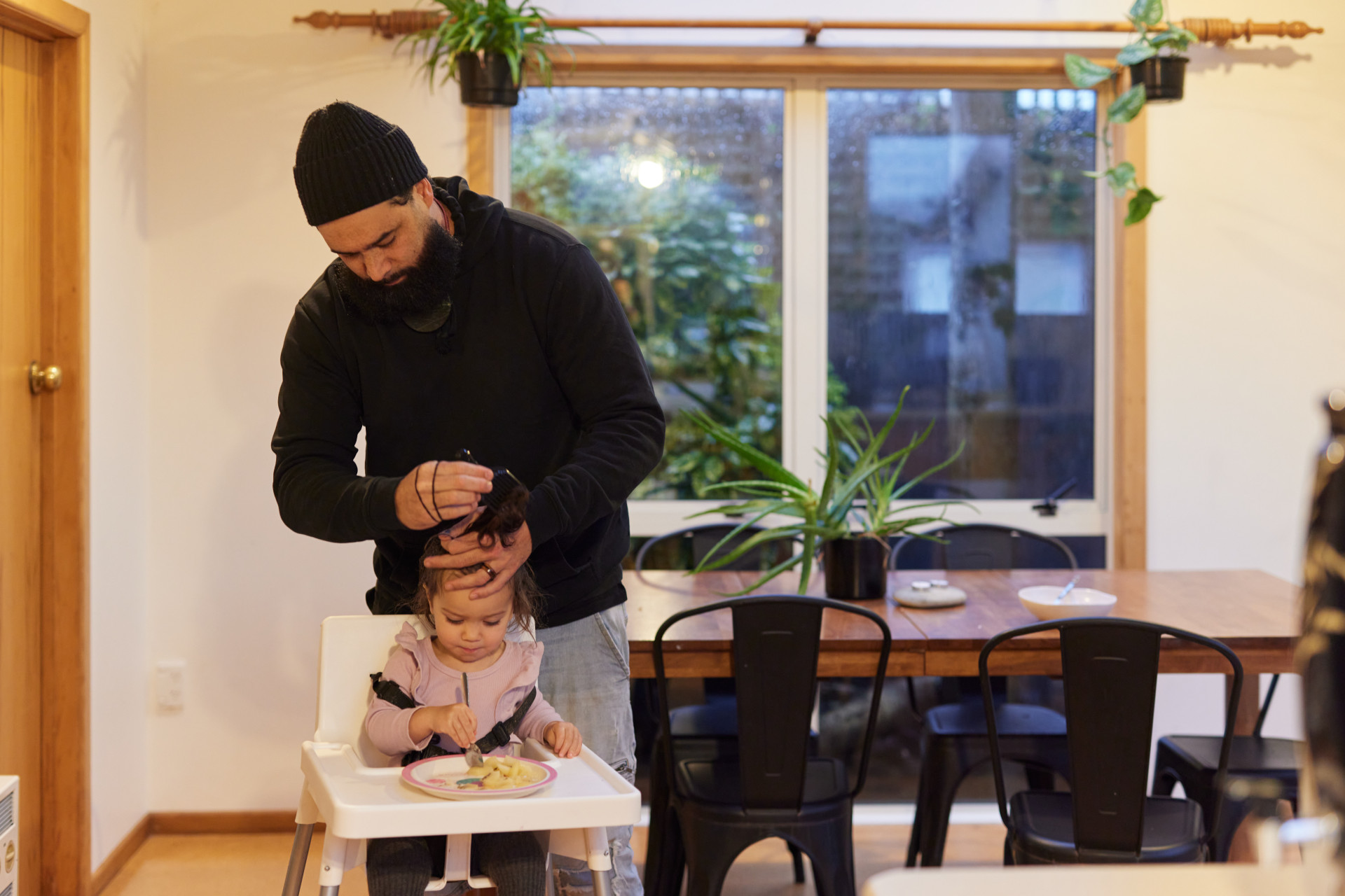 a man standing over a baby in a high chair