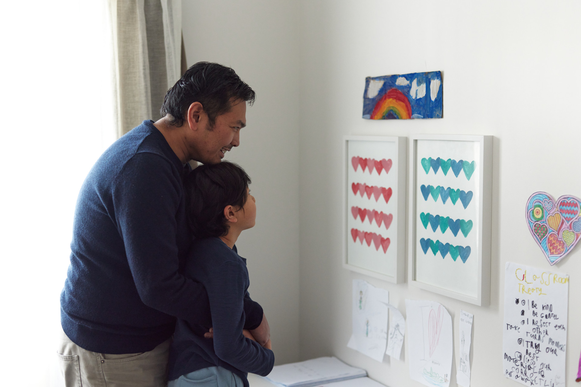 a man and a child are looking at artwork on a wall.	